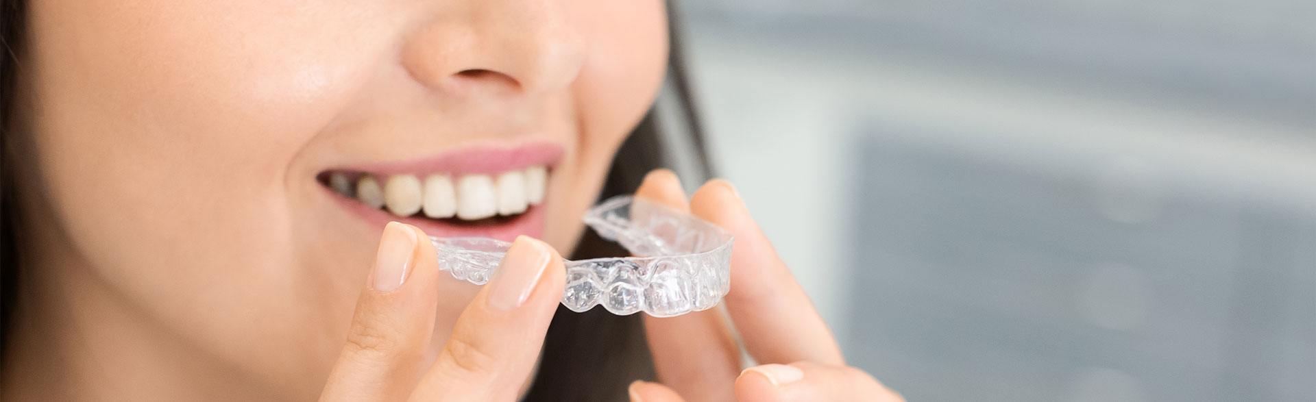 A woman holding a clear aligner, emphasizing invisible orthodontic solutions.