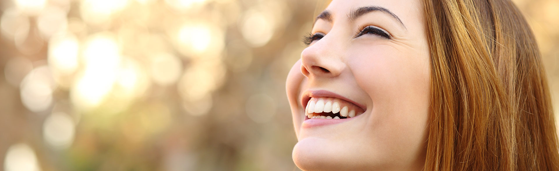 A smiling woman showcasing the natural appearance of metal-free crowns.