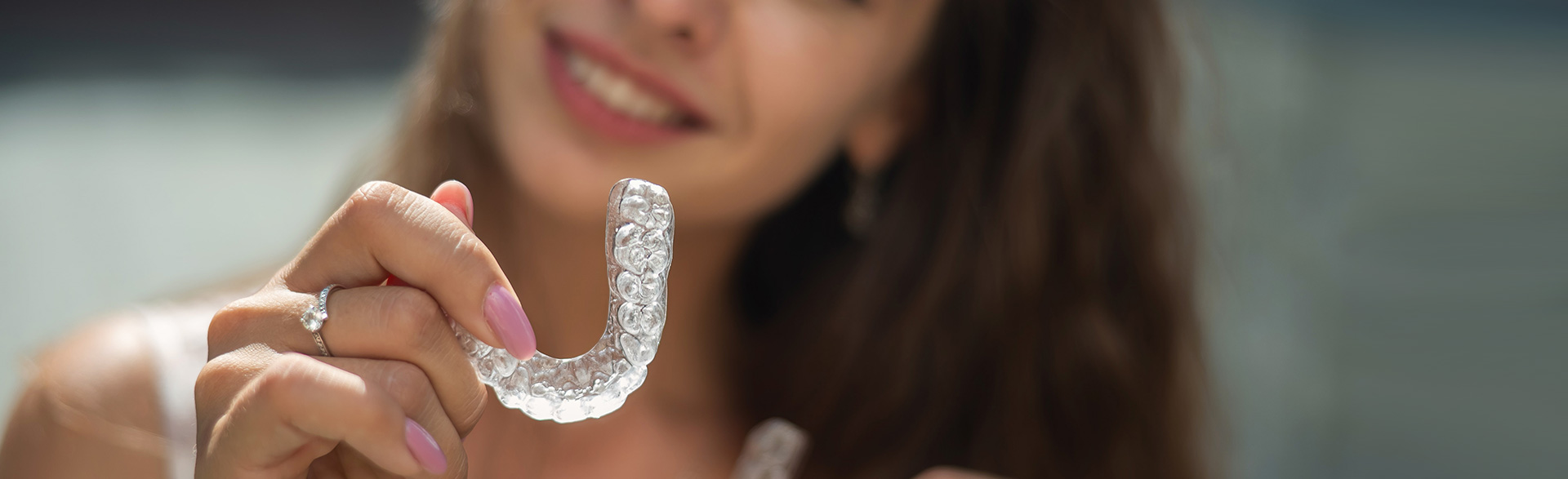 Invisalign banner with a model smiling, showcasing discreet teeth alignment options.