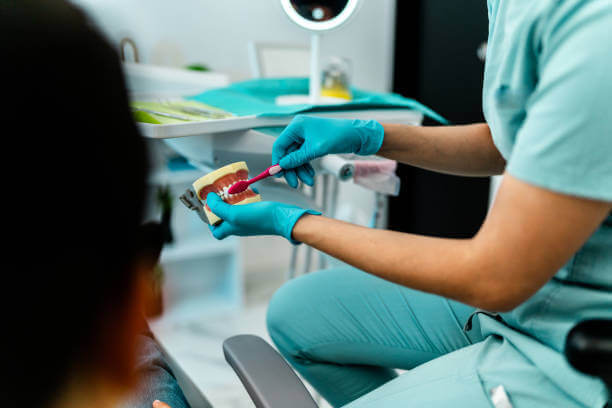 A dentist demonstrating proper brushing technique to a patient.