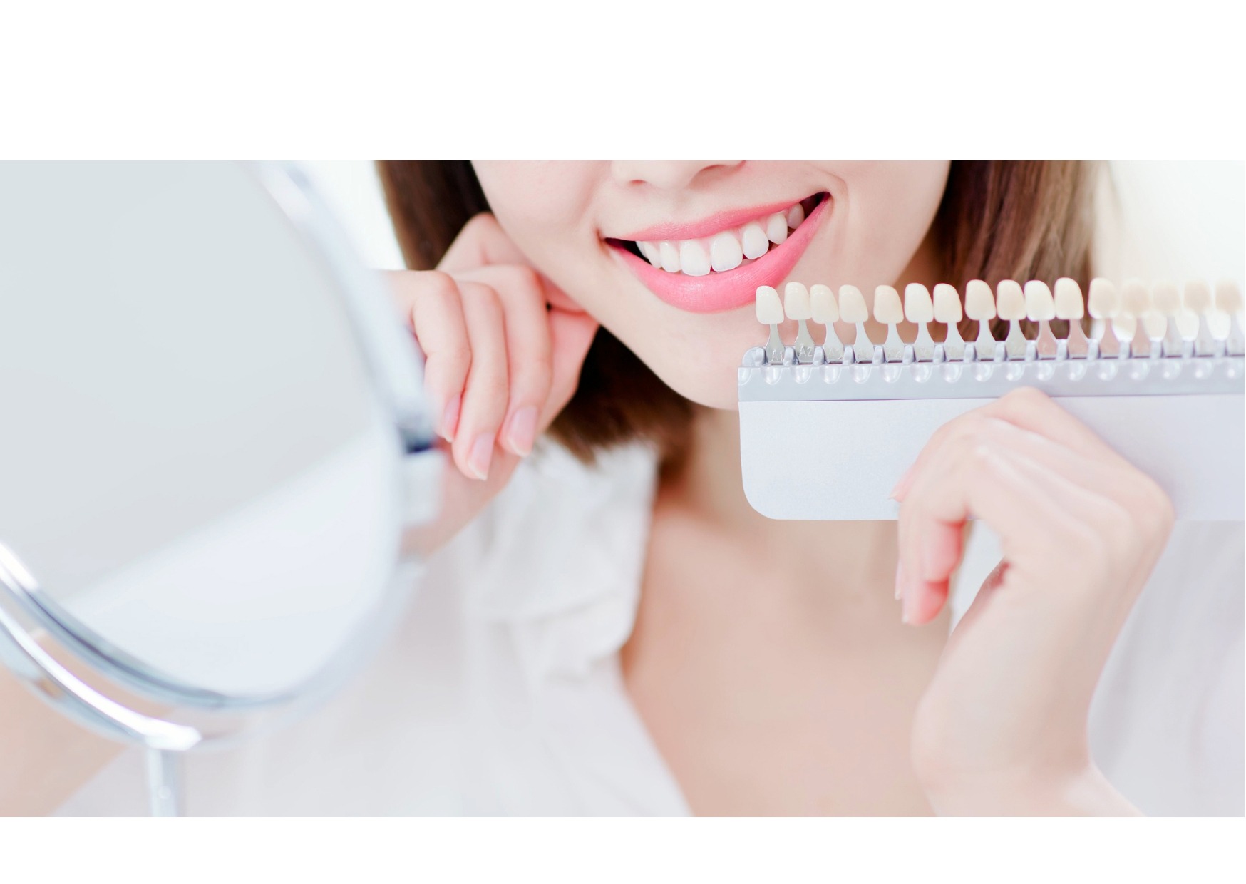 Woman comparing tooth shades using a dental shade guide to see teeth whitening results.