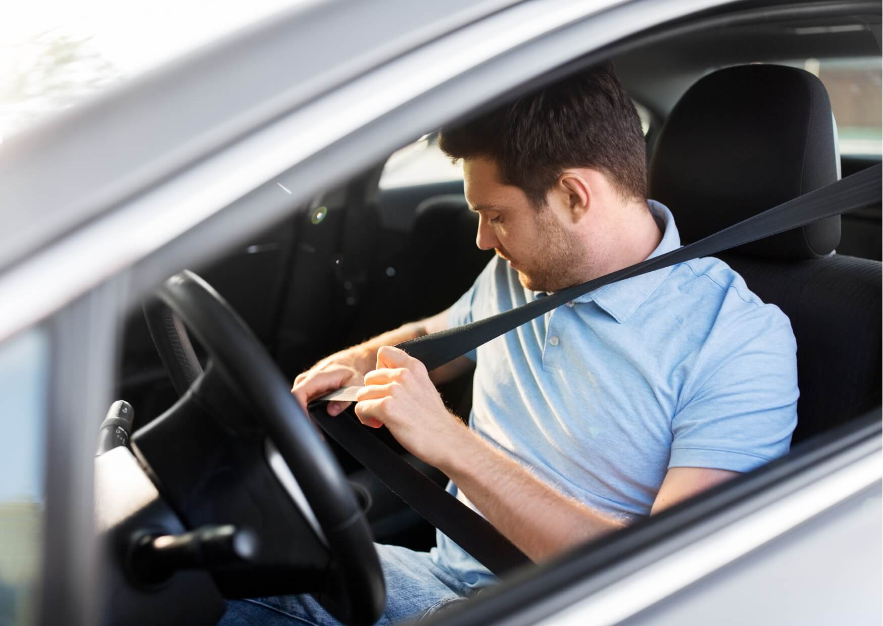 Man fastening his seatbelt before driving after a root canal treatment, illustrating when it may be safe to drive following the procedure.