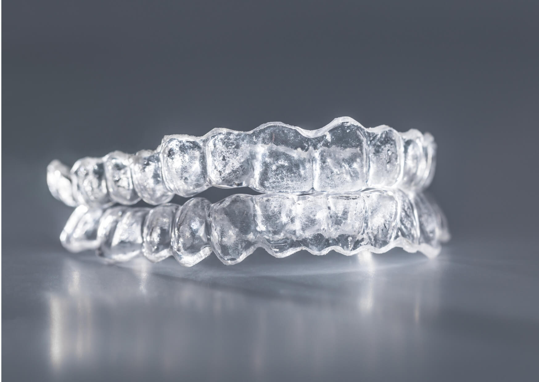 Clear custom nightguard for teeth displayed on a reflective surface, designed to help prevent damage from teeth grinding during sleep.
