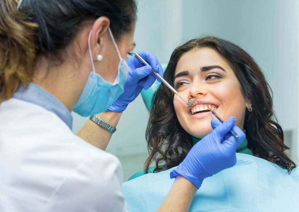 Dentist discussing a cosmetic dental bonding procedure with a smiling patient during a consultation about teeth bonding cost and treatment options.