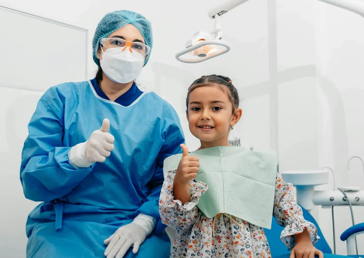 Pediatric dentist and young patient after a dental visit to check kids dental spacers and oral health.