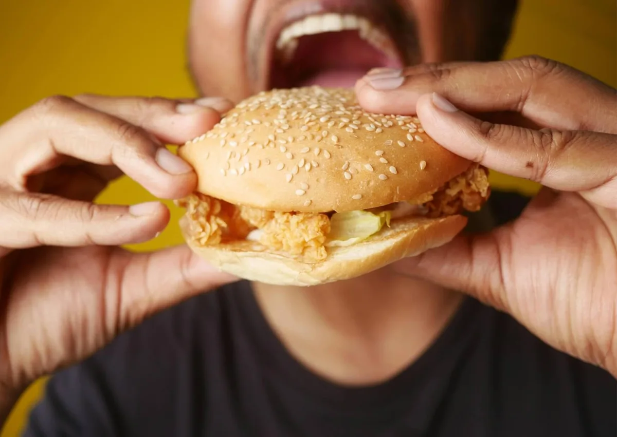 Person preparing to eat a burger after wisdom teeth removal and considering when solid foods are safe.
