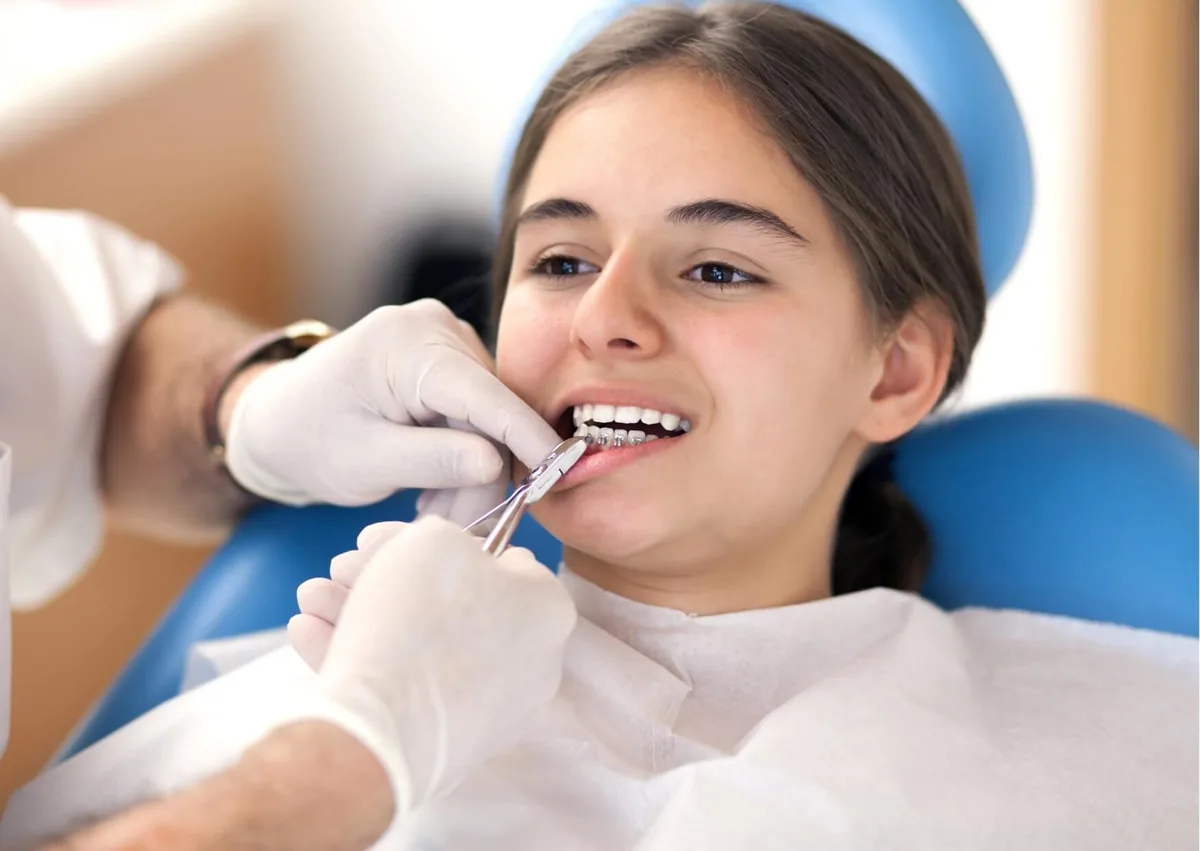 Patient having metal braces adjusted during an orthodontic visit while considering braces cost and treatment.