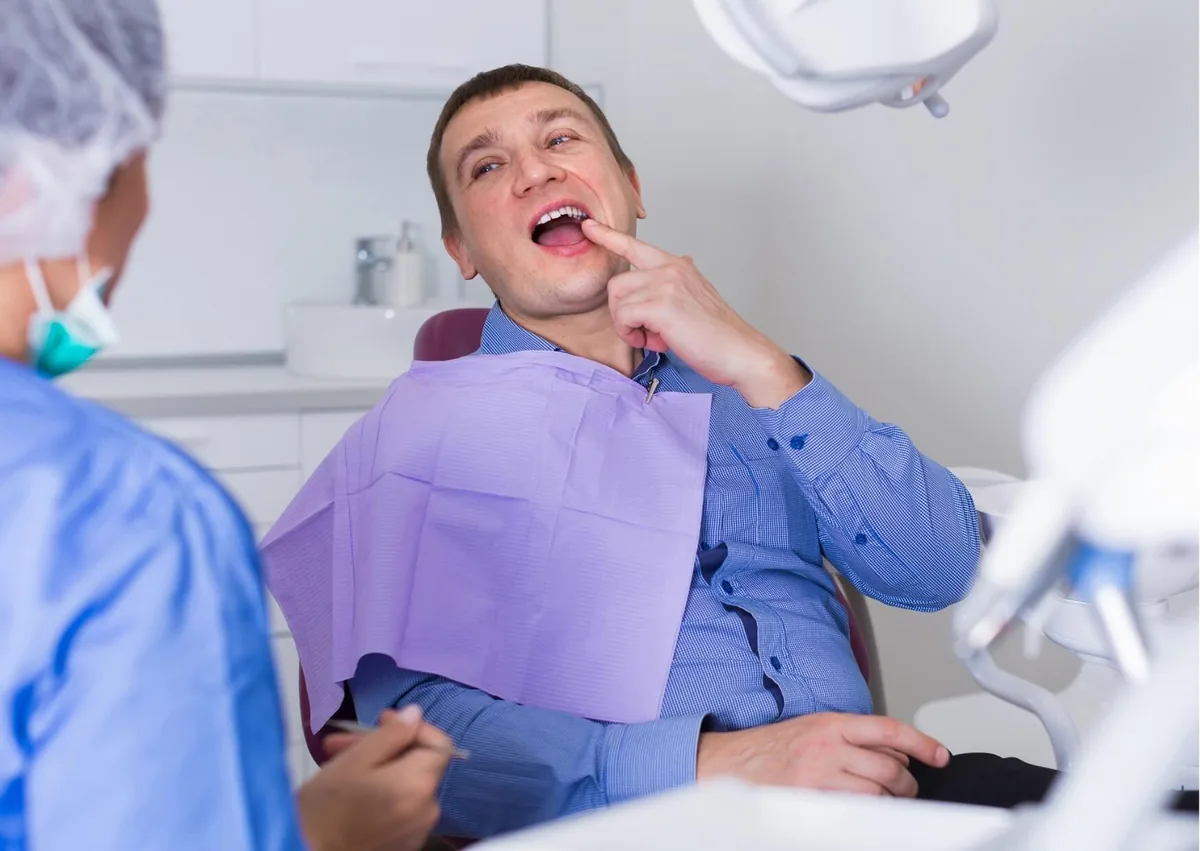 Patient pointing to a tooth during a dental visit while discussing what cavities look like and possible signs of decay.