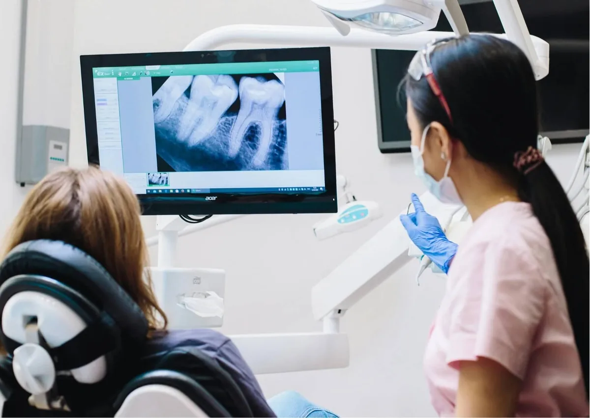 Dentist reviewing a dental X-ray with a patient to show what a wisdom tooth coming in looks like.
