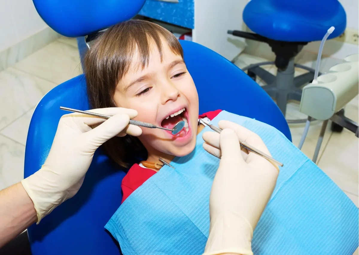 Dentist examining a child’s teeth during a routine pediatric dental checkup.