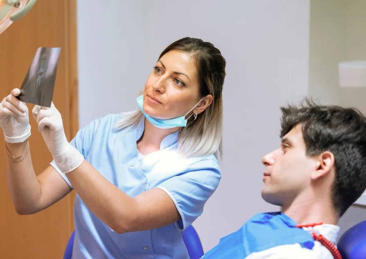 Dentist reviewing a dental X-ray with a patient while discussing affordable dental implants and treatment planning.