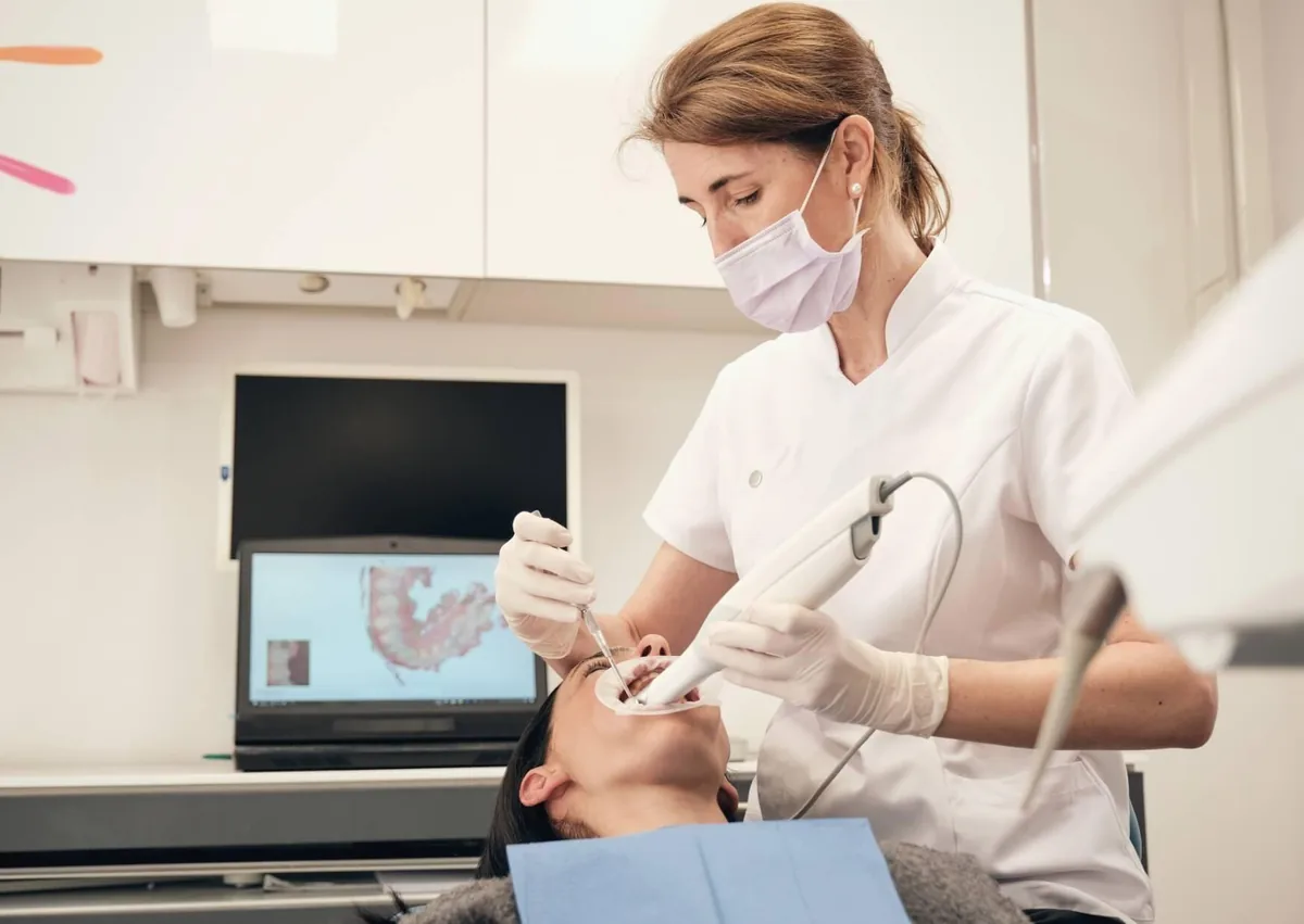 Dentist using a digital intraoral scanner to capture a patient's teeth for digital smile design and personalized cosmetic treatment planning.