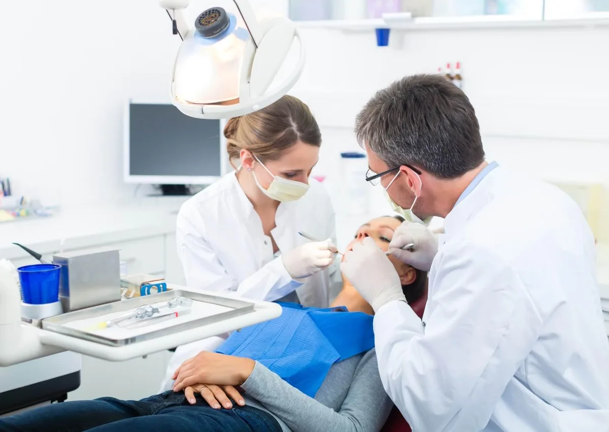 Dentist and dental assistant treating a patient in a dental chair, highlighting fluoride treatment and recommended waiting times before eating.