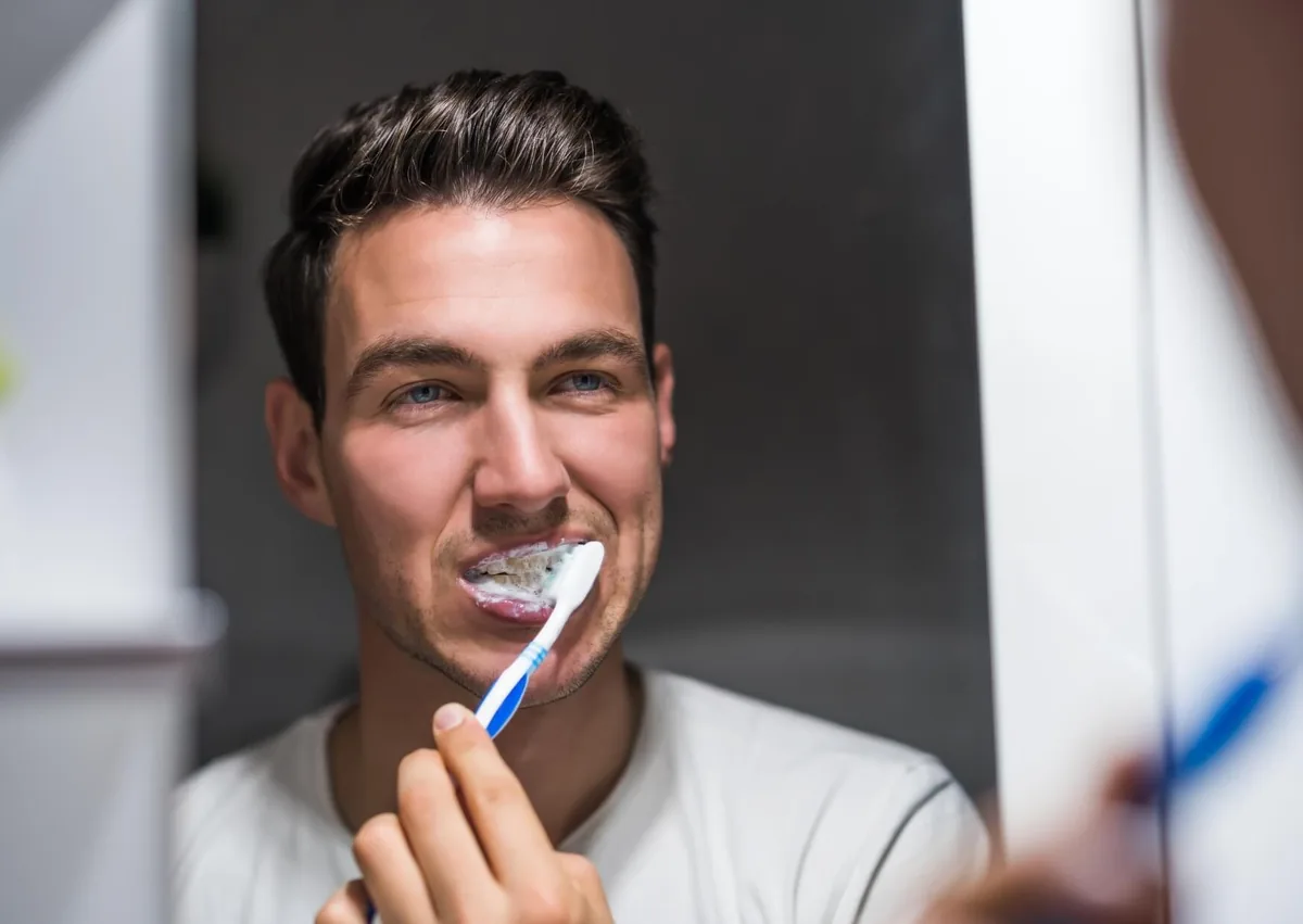 Man brushing his teeth to remove plaque buildup as part of a daily oral hygiene routine.