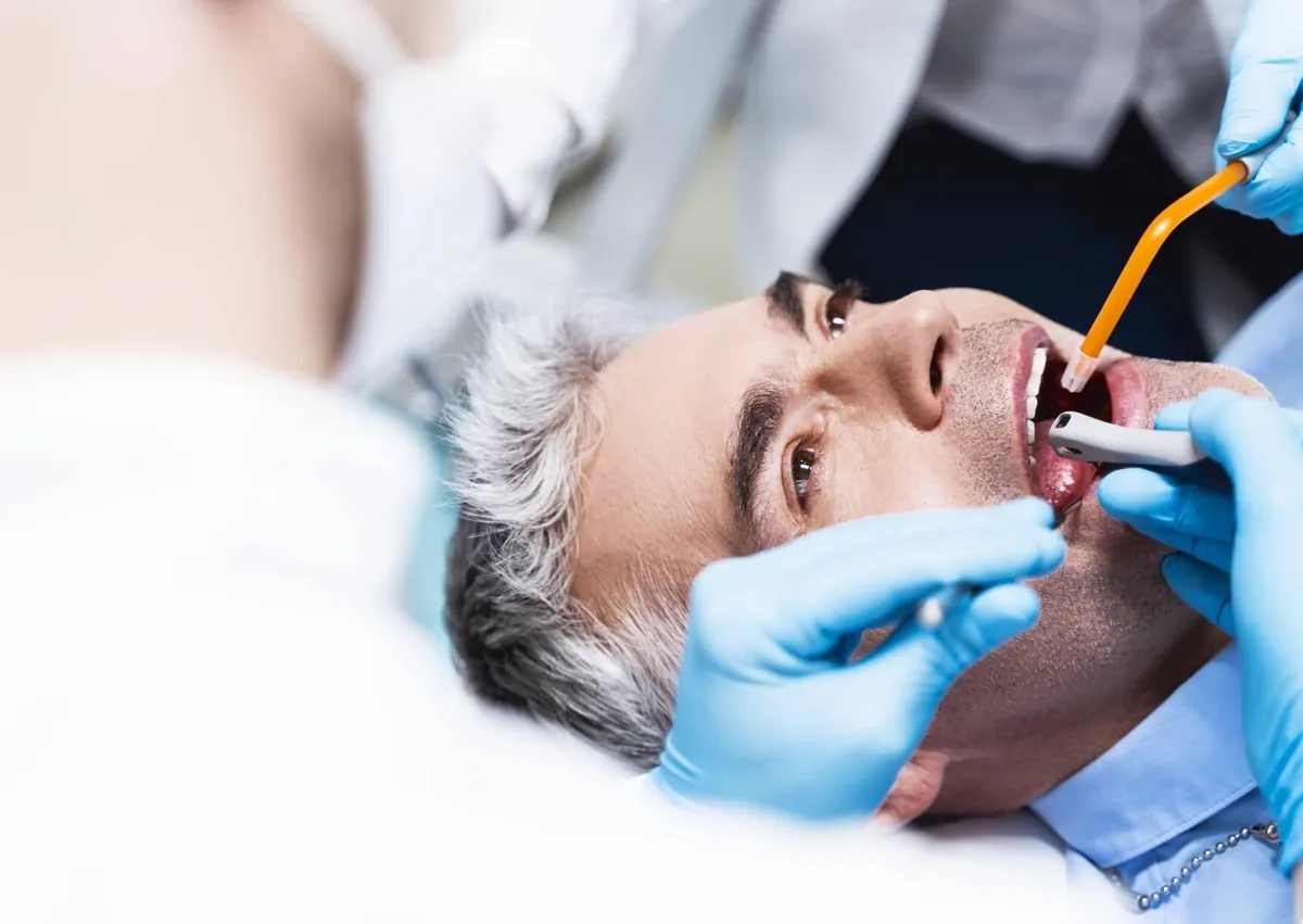 Dental professional removing plaque from a patient’s teeth during a professional dental cleaning.